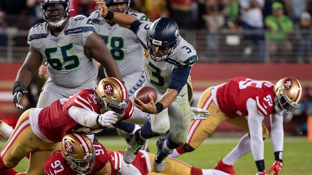 Seattle Seahawks starting quarterback Russell Wilson (3) eludes San Francisco 49ers’ Arik Armstead (91), San Francisco 49ers’ Nick Bosa (97) in overtime during a game at the Levi’s Stadium on Monday, November 11, 2019 in Santa Clara.