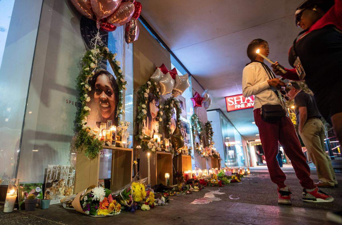 Valynda Cole, right of center, whose cousin Johntaya Alexander was one of the six people killed in the downtown Sacramento shooting early Sunday, stands next to a photo of her family member on the growing memorial for the victims Wednesday on 10th and K streets in downtown Sacramento.