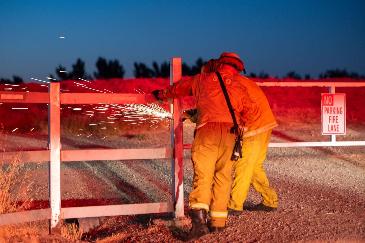 Two firefighters cut a lock to access a vegetation fire on Thursday night in Sacramento. First responders spent much of the night combating vegetation fires, structure fires and other Independence Day-related emergencies.