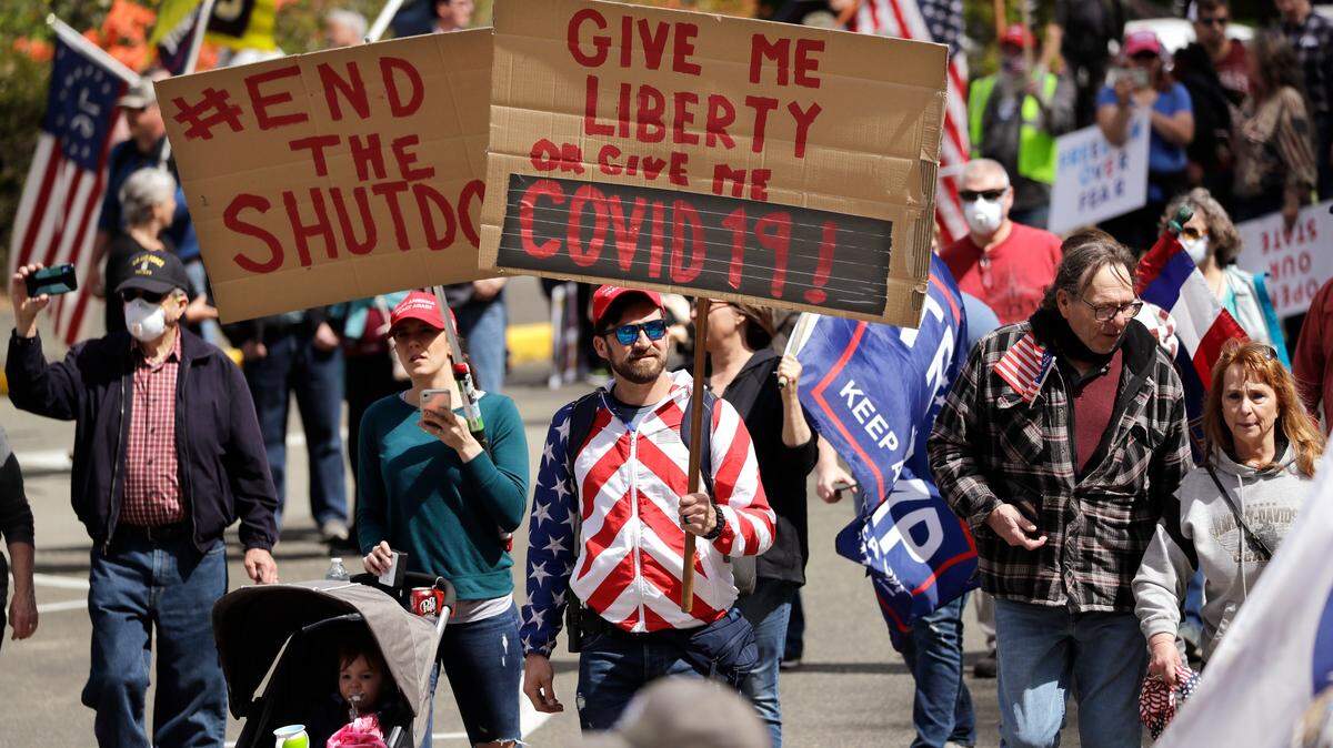 Demonstrators begin to gather at a protest opposing Washington state’s stay-home order to slow the coronavirus outbreak Sunday, April 19, 2020, in Olympia, Wash. Washington Gov. Jay Inslee has blasted President Donald Trump’s calls to “liberate” parts of the country from stay-at-home and other orders that are designed to combat the spread of the coronavirus. Inslee says that Trump is fomenting a potentially deadly “insubordination” among his followers before the pandemic is contained. (AP Photo/Elaine Thompson)