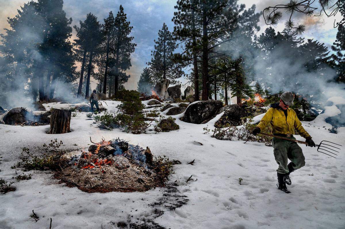 Firefighter Josh Wesson moves down a hill to check on other prescribed burn piles at Van Sickle Bi-State Park near South Lake Tahoe in February. The material was cut and piled two seasons ago.