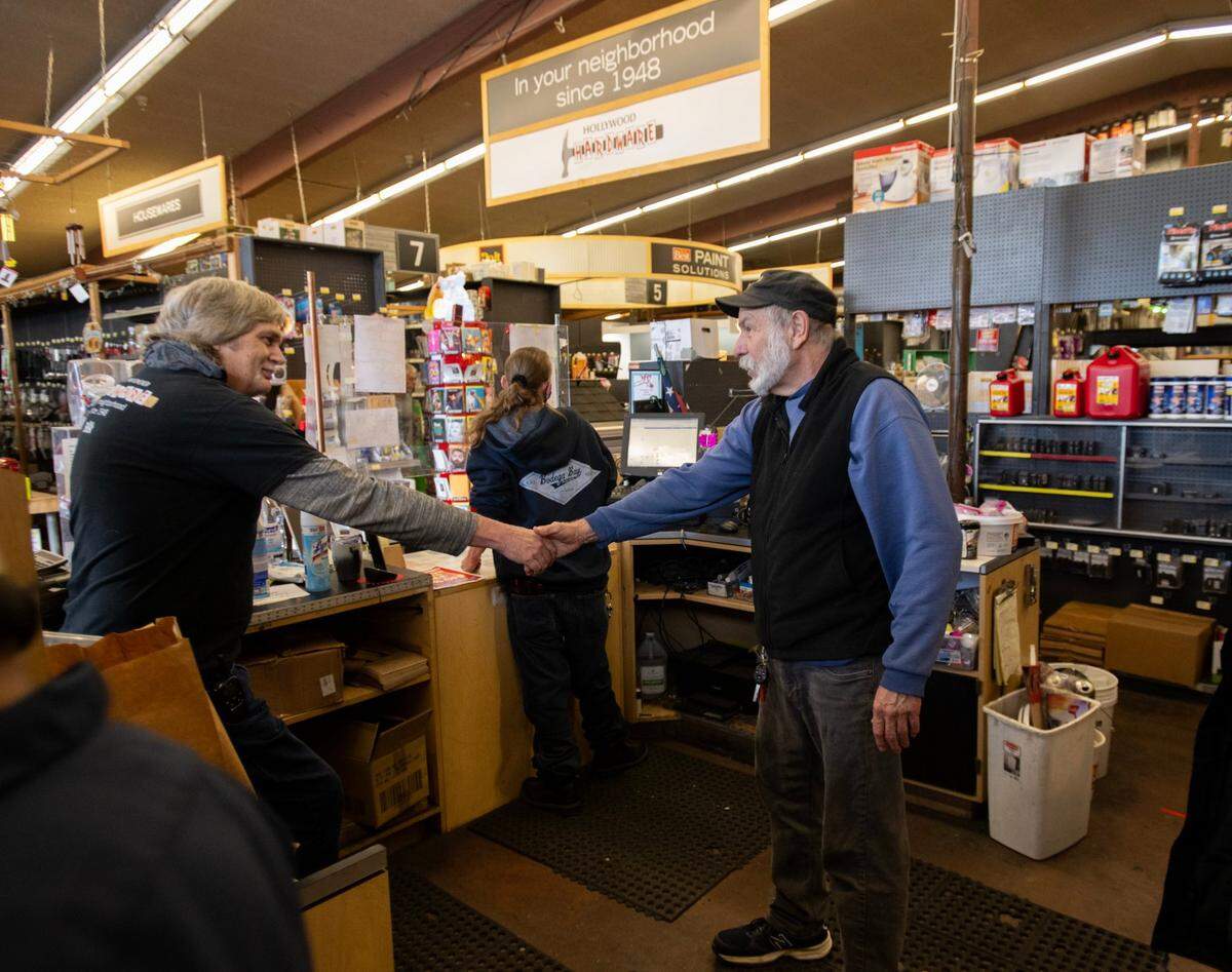Store manager Jeff Ford, left, who has worked at Hollywood Hardware for 27 years, shakes hands with a customer on Tuesday. The store will be closing its doors after 75 years.