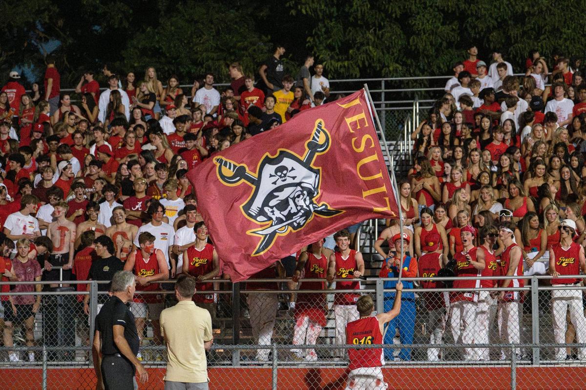 The Jesuit Marauders student section celebrates scoring during a rare night football game at Jesuit High School on Aug. 25.