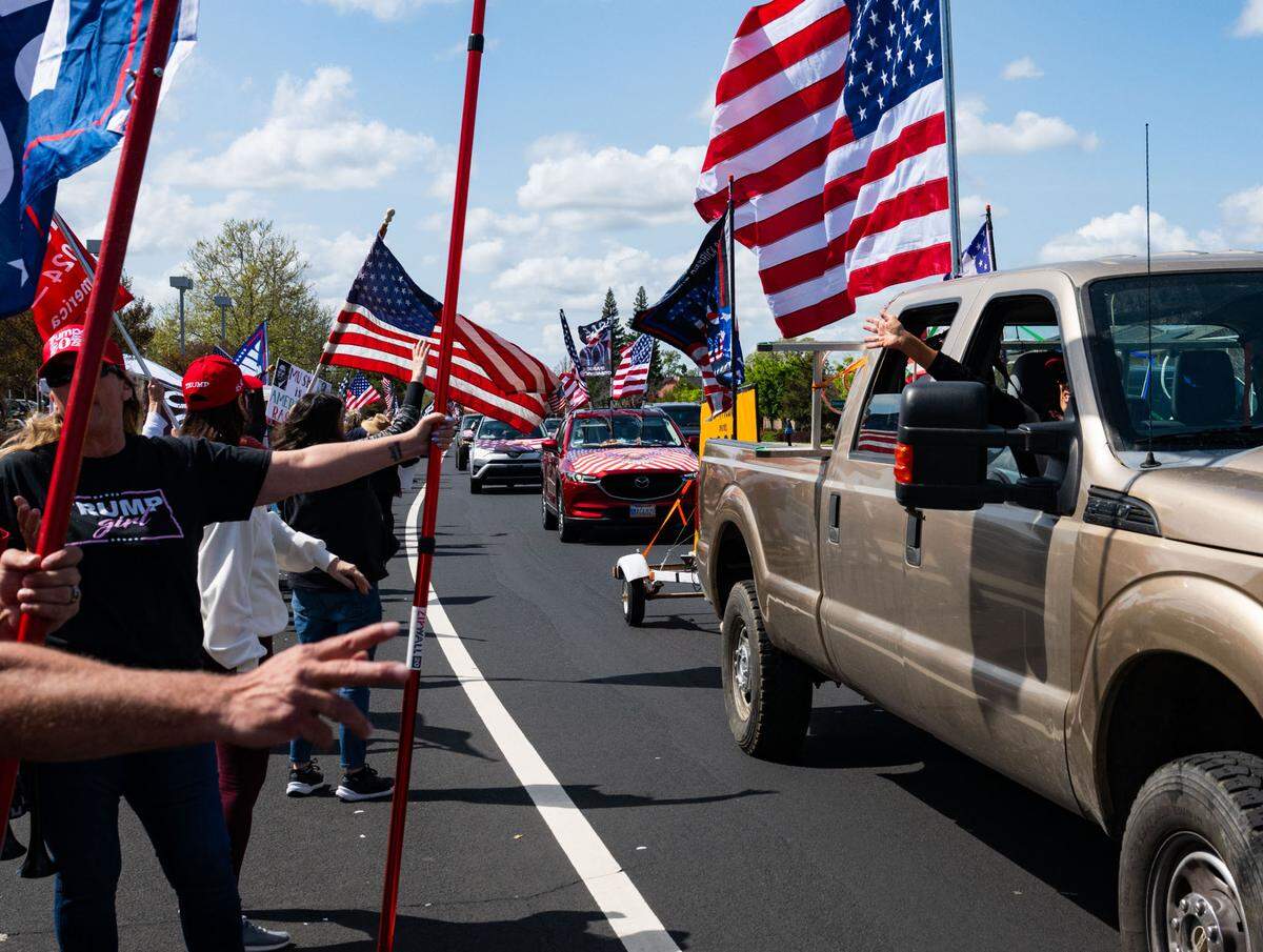 A convoy of Trump supporters drives past MAGA counter protesters on Granite Drive in Rocklin across from the Tesla dealership on Saturday, March 29, 2025.
