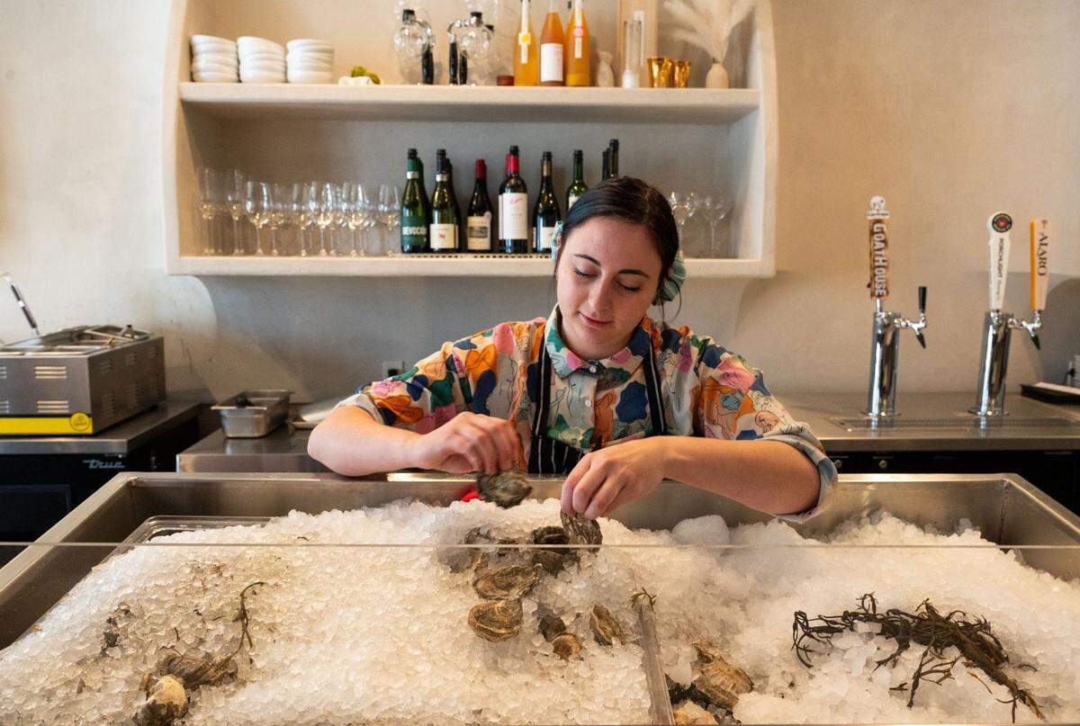 Omakase Por Favor owner Jeana Marie Pecha pulls oysters from the oyster bar Monday in midtown Sacramento. She believes raw bars are part of a trend of 2025 that favors healthy eating.