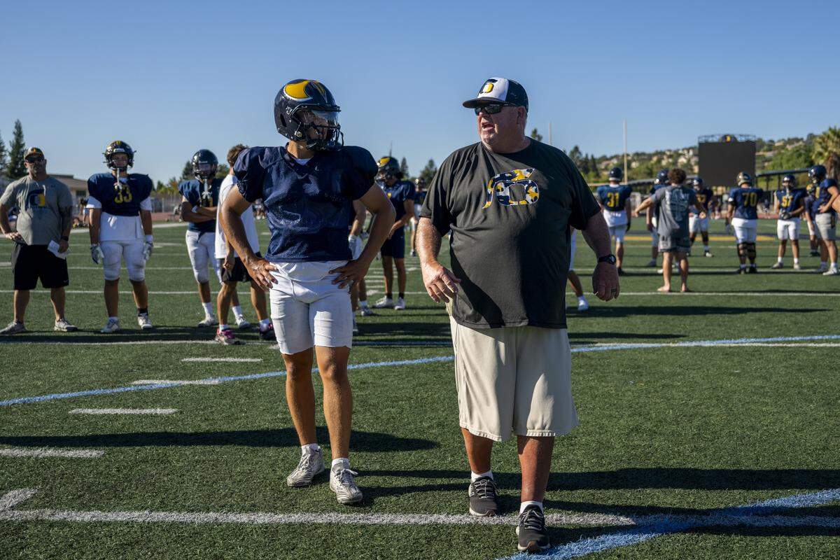 Javon Joseph, left, talks with head coach Casey Taylor between plays during a football practice at Oak Ridge High School in El Dorado Hills on Tuesday, Aug. 5, 2025.