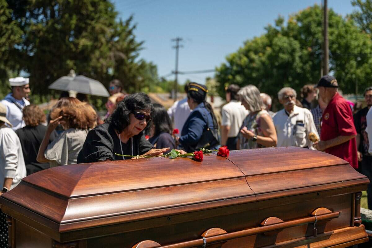 Gloria Medrano places a flower on the casket of her brother, Cpl. Albert Estrada, who was killed and missing in action during the Korean War, in St. Joseph’s Cemetery in Woodland on Wednesday.