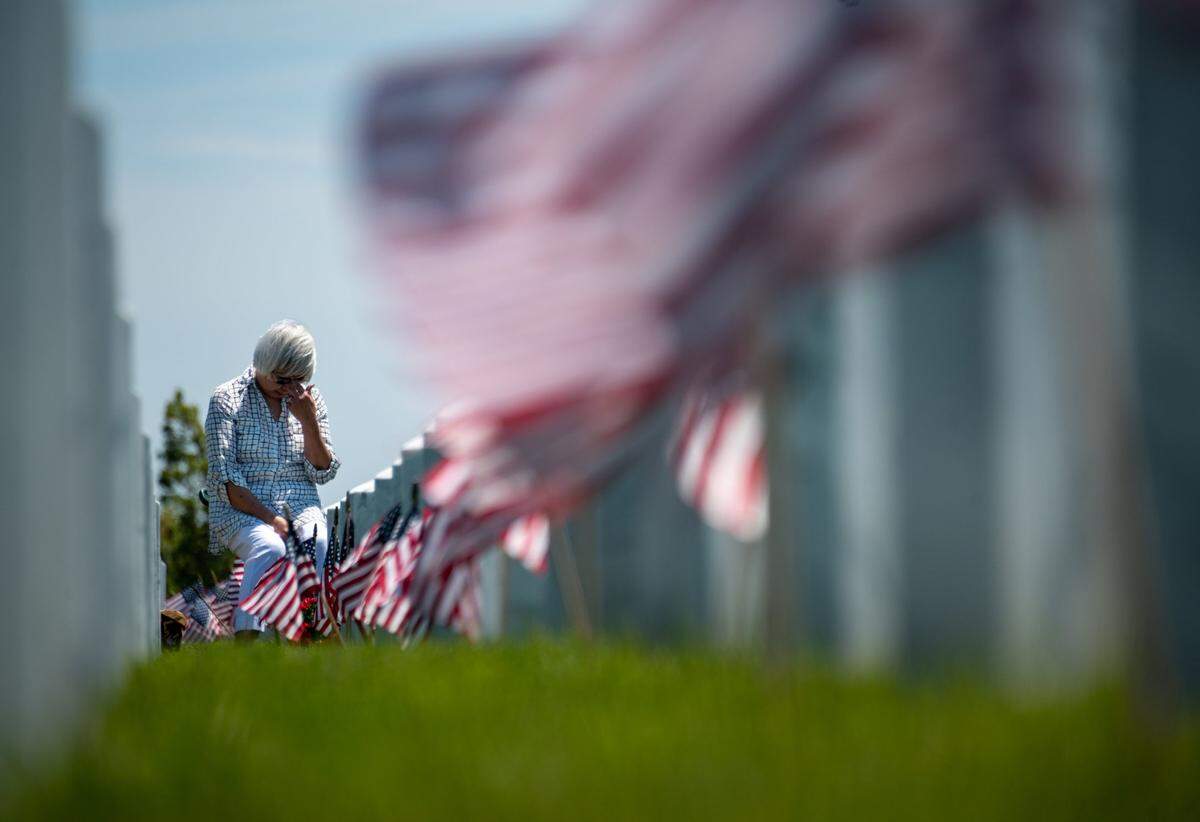 Noemi Bushman of Rancho Cordova sits at the gravestone of her husband Lt. Col. William Bushman during Memorial Day at Sacramento Valley National Cemetery in Dixon on Memorial Day, May 29, 2023. Her husband was a B-52 pilot during the Vietnam War and they were married for 28 years.