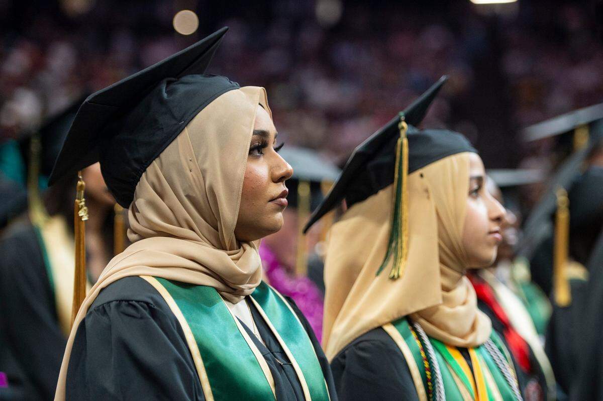 Radhiyah Aanisah Koya, left, and Hijab Sajid, right, listen to the speakers during the Sacramento State College of Business commencement on Friday.