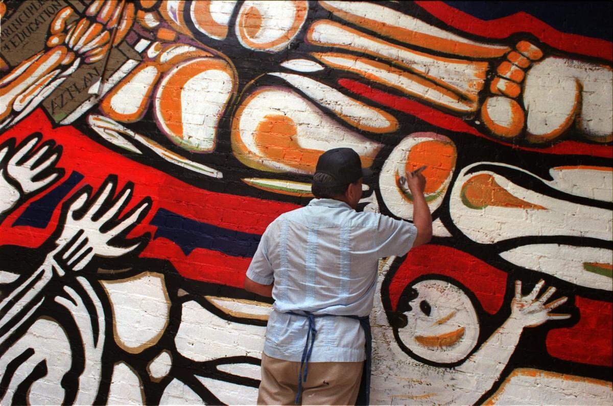 Esteban Villa, a retired art teacher from Sacramento State, restores a mural in 1997 that he and his students painted in the Washington Neighborhood Center in 1971. 