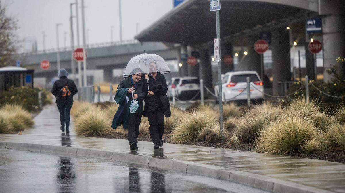 Pedestrians walk in the rain at the Sacramento International Airport on Tuesday, Dec. 27, 2022. The city continues to experience wet weather patterns into January.