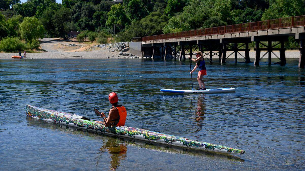John Weed and Nicole Young practice kayaking and paddleboarding for the Great American Triathlon on the American River on Tuesday, July 16, 2019, in Rancho Cordova.