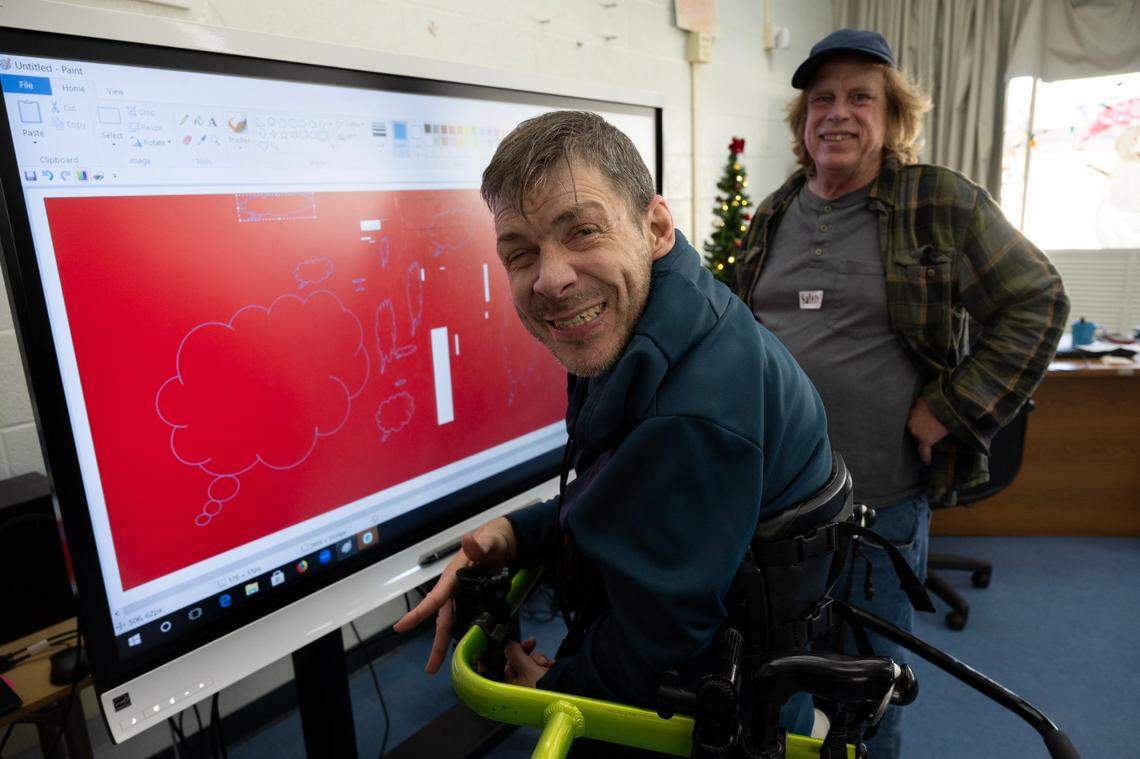 Adam Badger smiles after creating artwork on an interactive screen with art teacher Jim Mansfield on Monday at UCP of California, an adult day care program for people with disabilities in Foothill Farms. The program hopes to purchase another screen and stand with funding from The Book of Dreams.