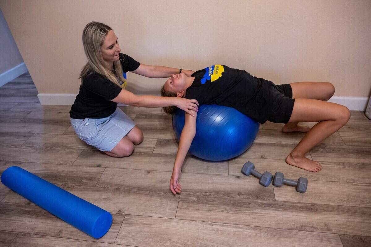 Svitlana Iotko helps her daughter Anastasia, 12, on July 21, who suffers from scoliosis during her physical therapy exercises at home in Fair Oaks. “My daughter has scoliosis and the doctor at Elica was so nice that she referred us to physical therapy so we are pretty happy to have these people as friends,” said Iotko.