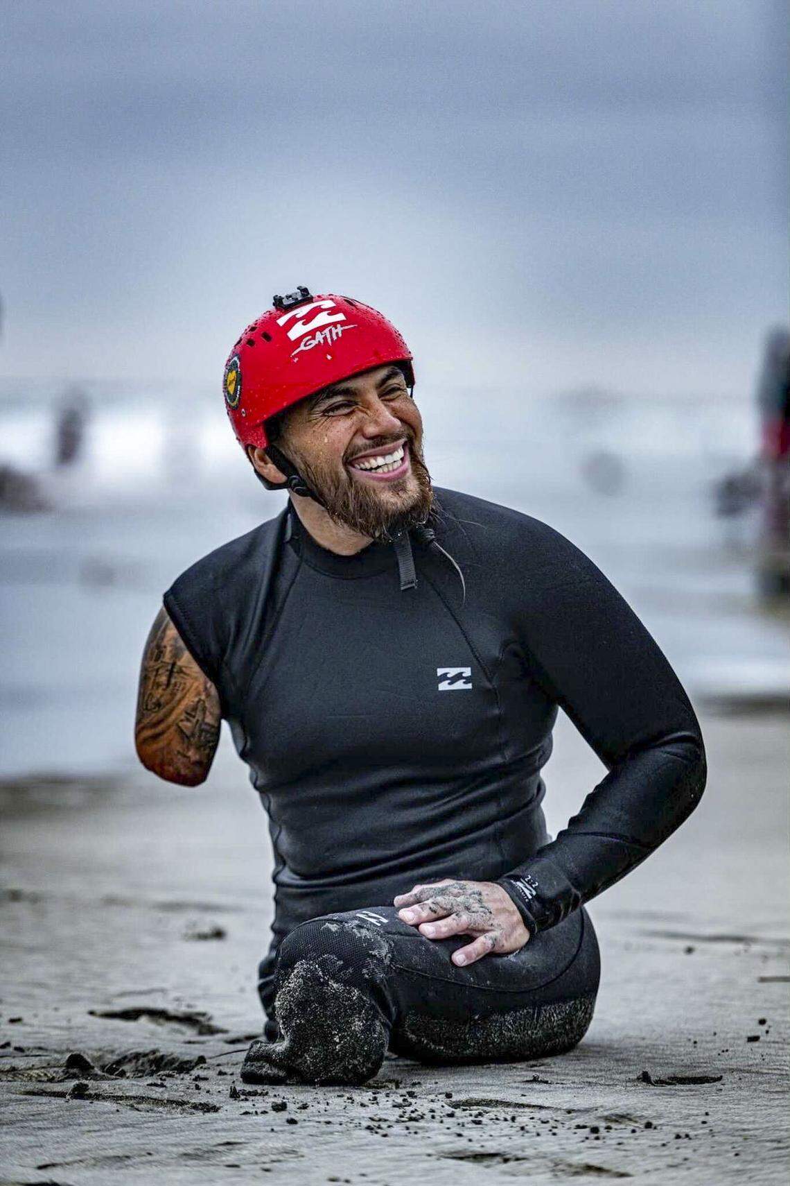 Jose Martinez laughs with friends while sitting on the beach at Oceanside Pier after getting in some surfing practice last year. He won a gold medal in the 2021 World Para Surfing Championship.