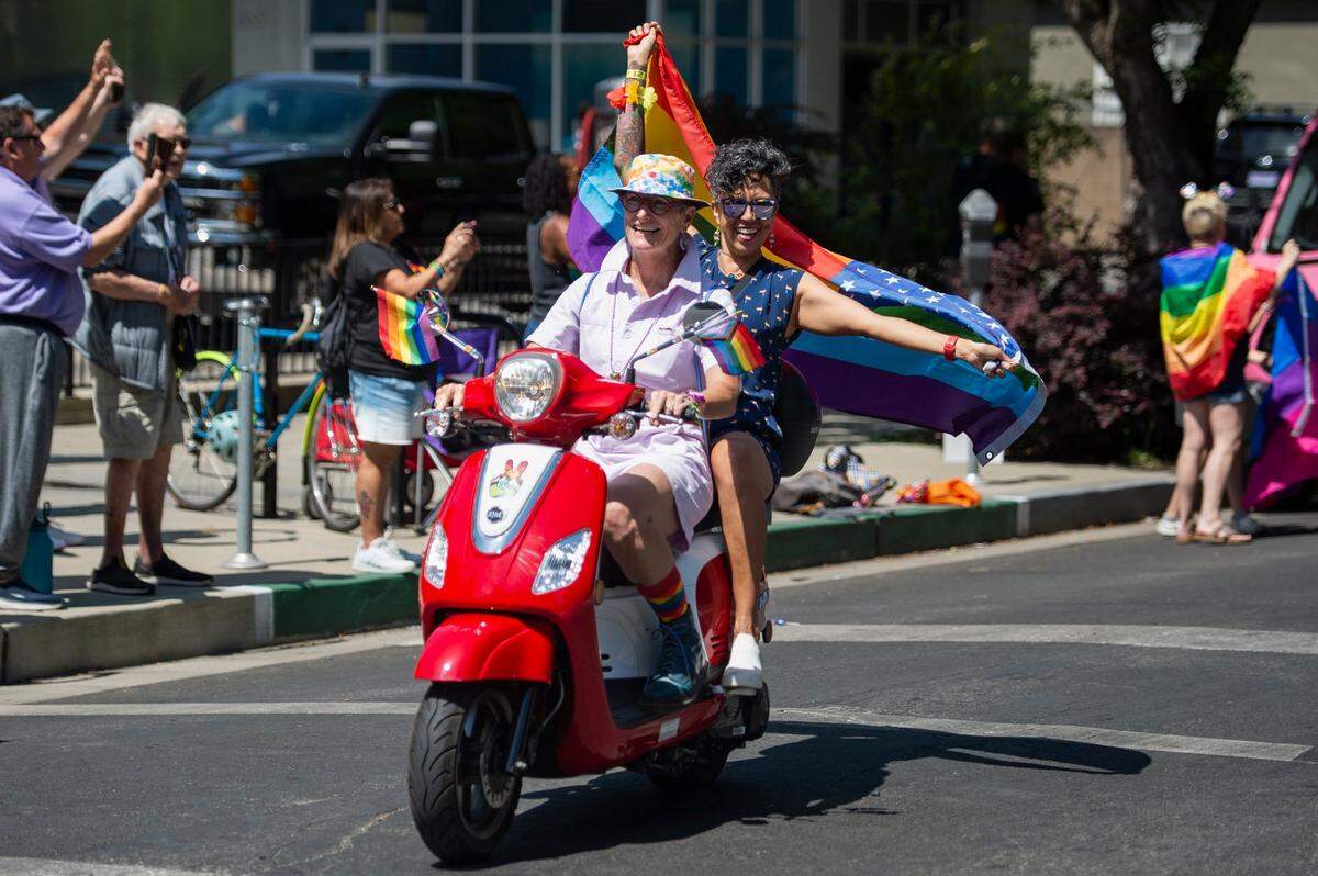 Leah Morris drives while her wife Veronica Perez holds the rainbow flag during the Sacramento Pride March and Parade on Sunday, June 11, 2023. This was their 19th year attending the parade.
