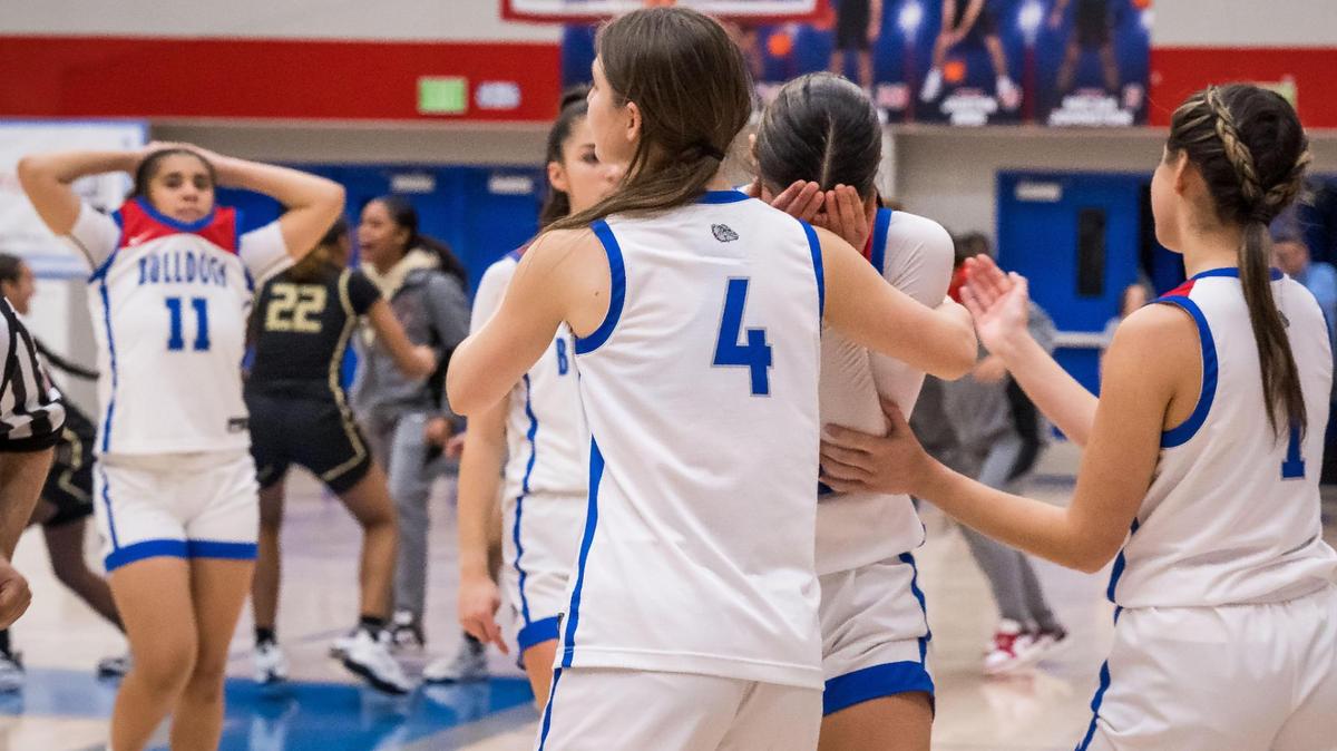 Folsom Bulldogs guard/forward Charlotte Climenhage (21), center, is comforted by teammates guard Faith Russell (4), left, and guard Celeste Johnson (1) — all seniors — after their loss in double overtime to the Salesian (Richmond) Pride at the CIF Northern California Open Division high school girls basketball first round playoff game Wednesday, March 1, 2023, at Folsom High School. Folsom guard Aryn Bright (11), far left, walks past celebrating Salesian players in the background.