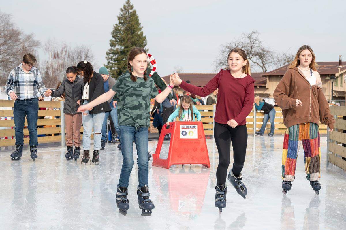 Cousins Cora Wong, left, 11, and Jules Ochoa, right, 11, hold hands while skating on Sunday, Dec. 24, 2023, at Folsom Historic District Ice Rink.