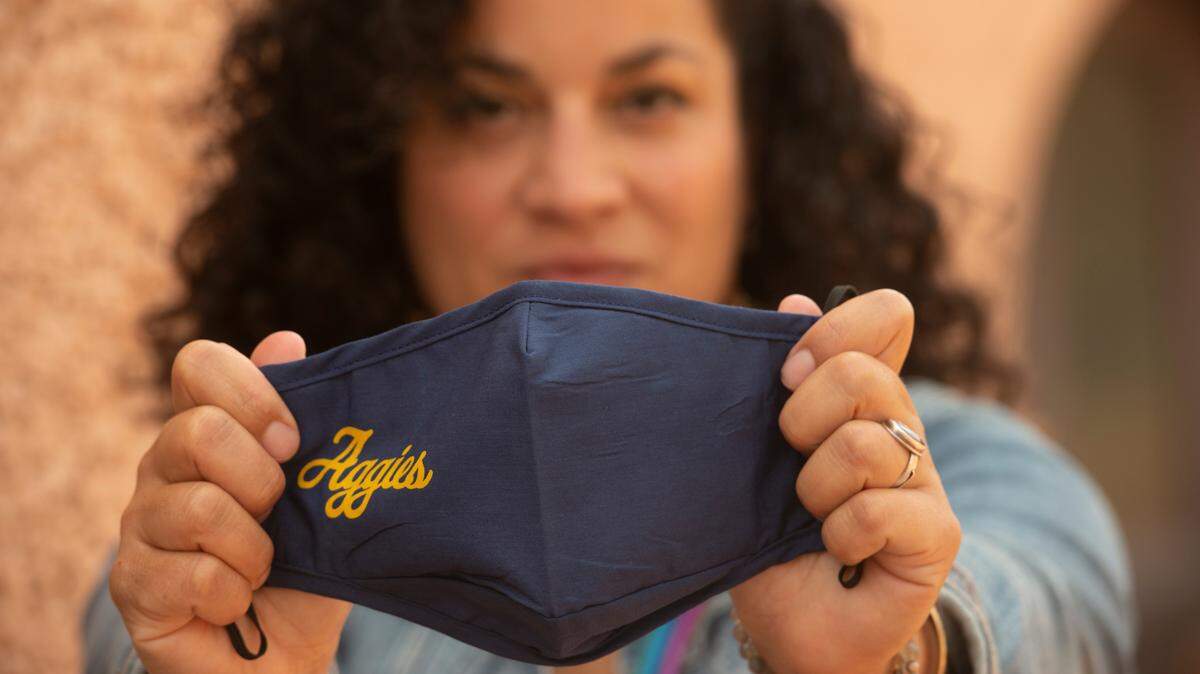 Sequoia Erasmus, a masters student at UC Davis, shows off the two designs of branded face coverings. Face coverings are required on the campus, and the campus will distribute thousands of these branded face coverings, some of them in welcome kits for students.