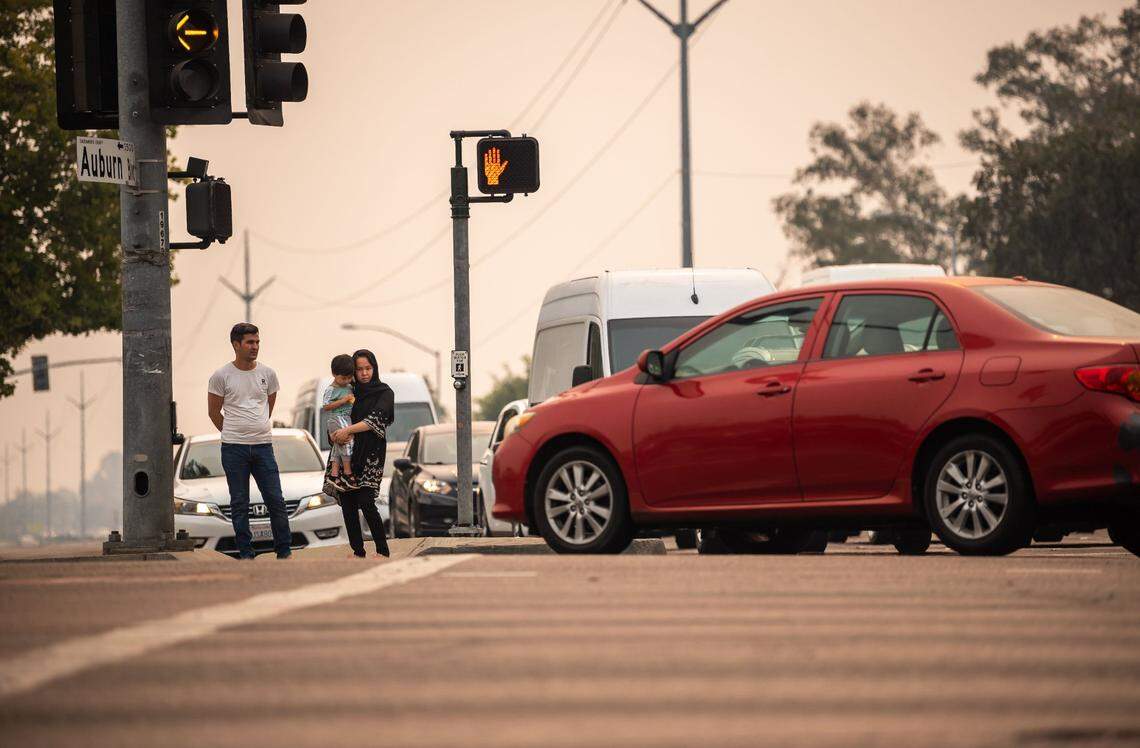 Ramin Khaliqyar, left, who moved from Afghanistan to Sacramento over five years ago, waits with his wife, Nadira Zafari, and son, Artin Khaliqyar, 2, to cross Watt Avenue at the Auburn Boulevard crosswalk on their way to the store Thursday, Aug. 19, 2021, in Sacramento. The intersection is a very dangerous place for me and other people, he said, adding that his family lives nearby and they cross there every day.