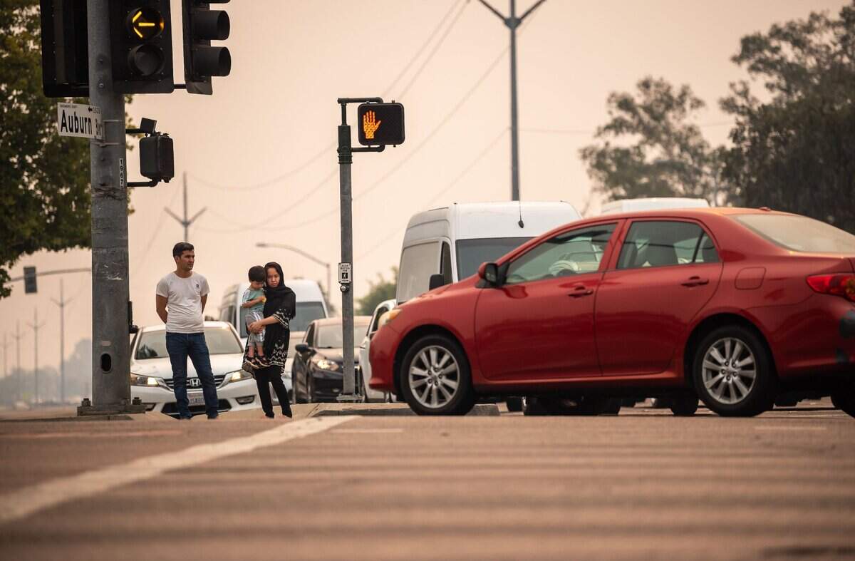 Ramin Khaliqyar, left, who moved from Afghanistan to Sacramento over five years ago, waits with his wife, Nadira Zafari, and son, Artin Khaliqyar, 2, to cross Watt Avenue at the Auburn Boulevard crosswalk on their way to the store Thursday, Aug. 19, 2021, in Sacramento. The intersection is a very dangerous place for me and other people, he said, adding that his family lives nearby and they cross there every day.