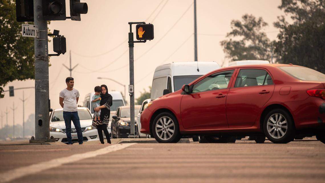 Ramin Khaliqyar, left, waits with his wife, Nadira Zafari, and son, Artin Khaliqyar, then 2, to cross Watt Avenue at the Auburn Boulevard crosswalk in 2021. Sacramento County releases data on the number of cars on unincorporated roads. Watt Avenue and others have traffic levels on par with some California highways.