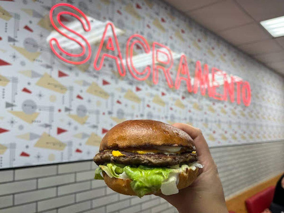 Audience journalist JJ Juarez holds up a burger at Lucky’s Drive-in Sacramento.