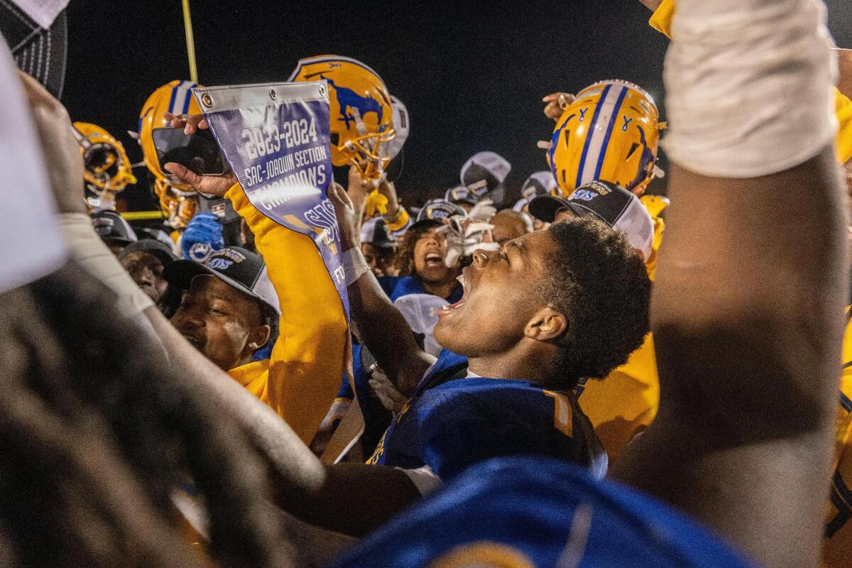 Grant Pacers running back Wayshawn Parker (1) celebrates with his teammates, and the CIF Sac-Joaquin Section Division III championship banner, after their title victory against the Woodcreek Timberwolves on Friday, Nov. 24, 2023, at Hughes Stadium.