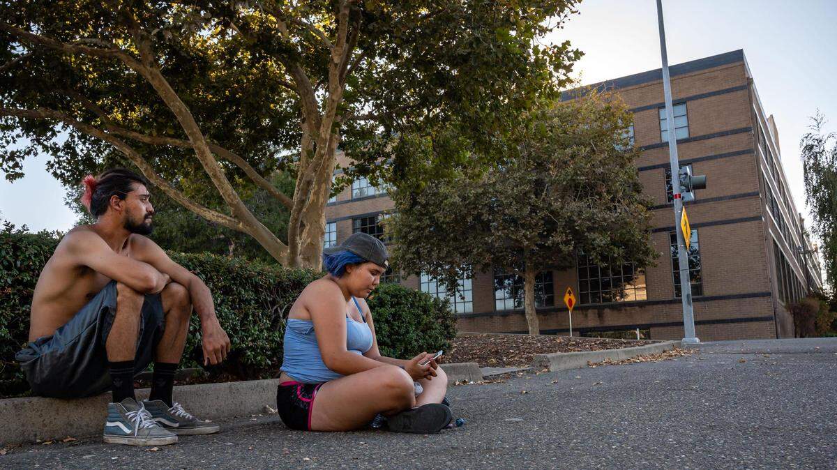 Jasmine Belarmino, center, and John have been waiting to secure housing for about a year while sleeping in a tent nearby to a five-story building at Third and R streets, right, that is owned by the California Public Employees’ Retirement System and sits vacant Saturday, Aug. 20, 2022, in downtown Sacramento. Sacramento County officials killed a long-planned proposal, developed with the city, to create a shelter that would have housed hundreds of homeless people downtown, according to people familiar with the deal.