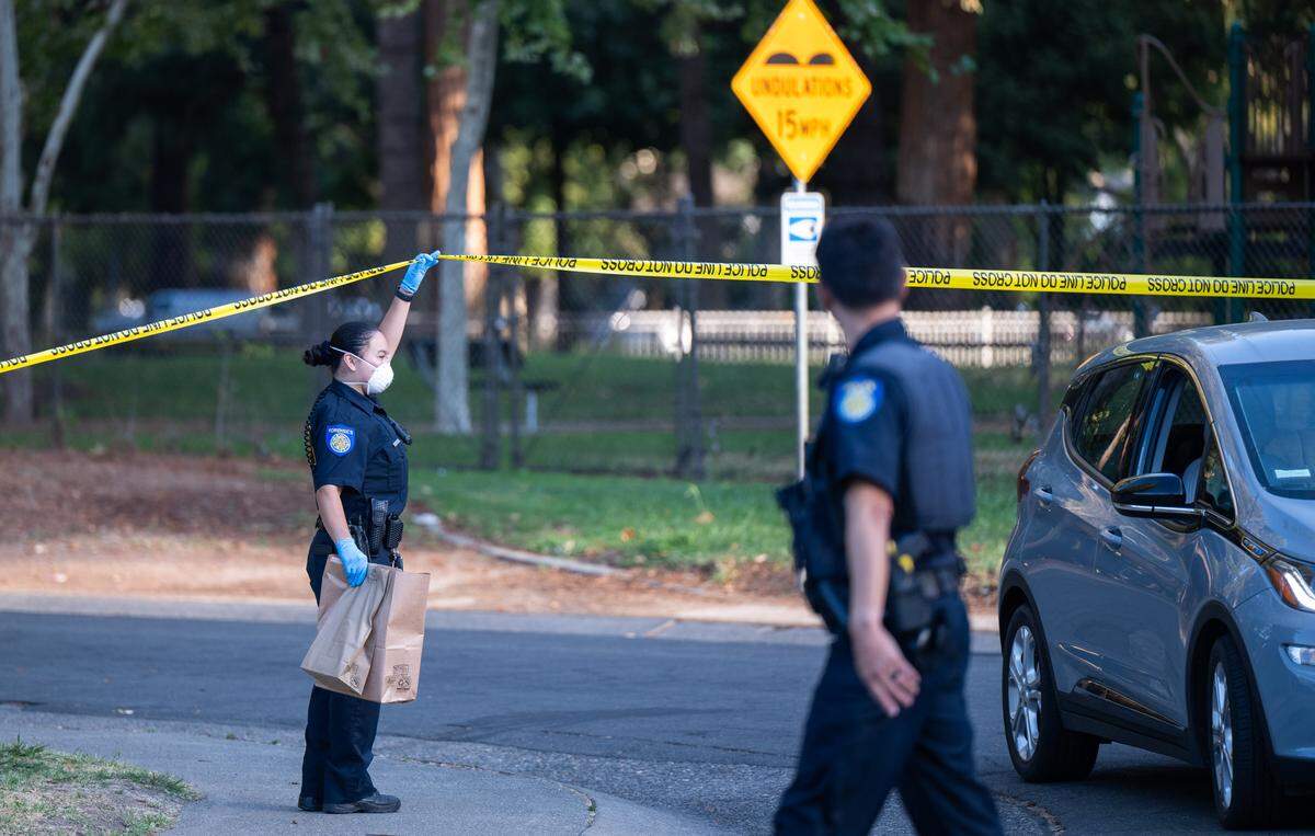 A Sacramento police officer helps a resident drive out of a crime scene on 13th Avenue in Land Park on Thursday, Aug. 14, 2025.