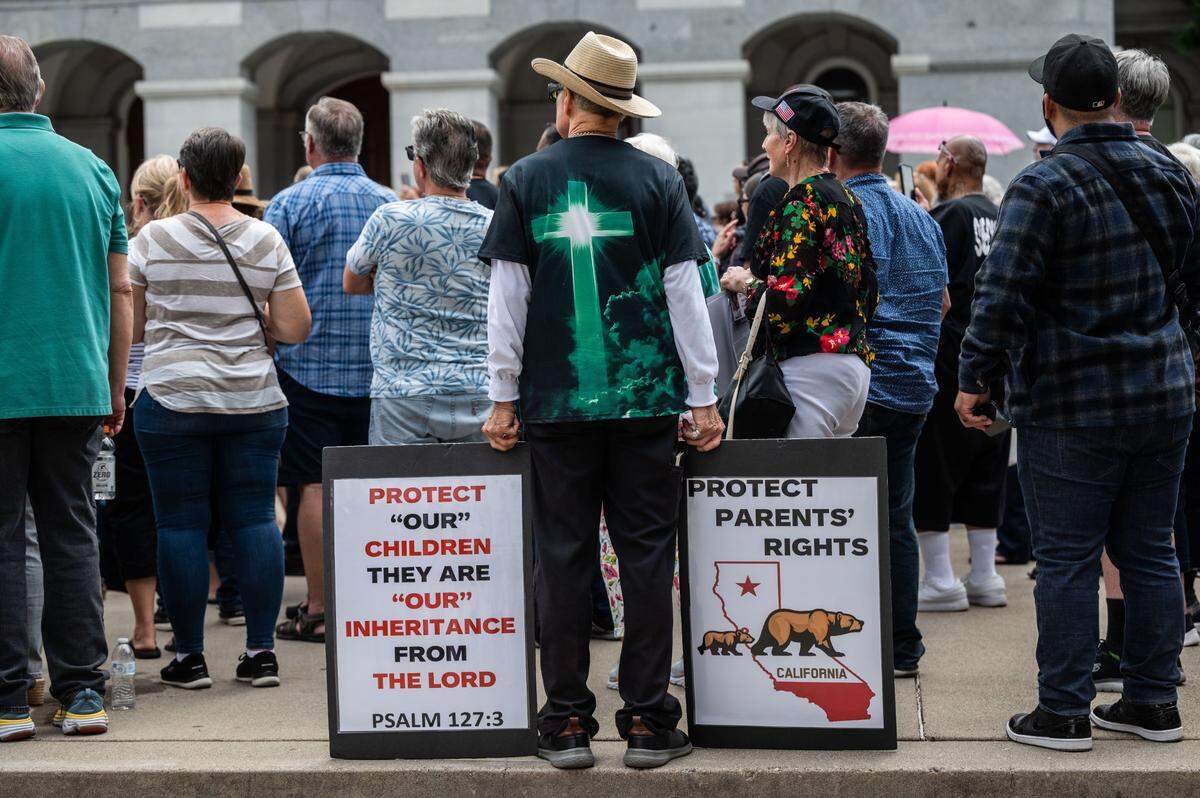Terry Tucker of Dixon holds signs as he participates in a “parental rights” rally at the state Capitol on Monday.