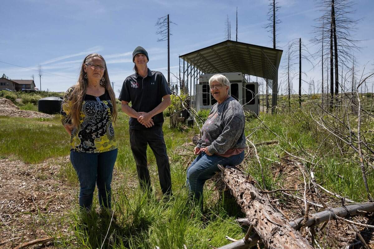 Jenny Magidson, 67, Tobe Magidson, 49, and Penny Singleton, 68, on Friday, May 1, 2026, stand outside the trailer where Jenny Magidson has lived since the 2021 Caldor Fire. Tobe Magidson bought the property after the fire destroyed his home. Rising home insurance rates as a result of the fires is just one challenge the new commissioner will face.