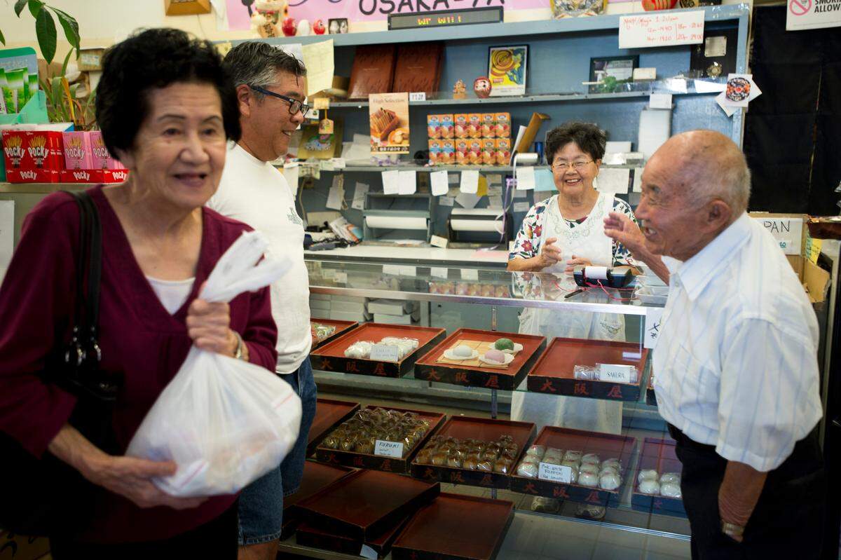 Etsuko Dote rings up a sale of an assortment of manju and mochi purchased by Alan Nakagawa, center, and his parents Mary and Fred at Osaka-Ya in Sacramento in 2013.