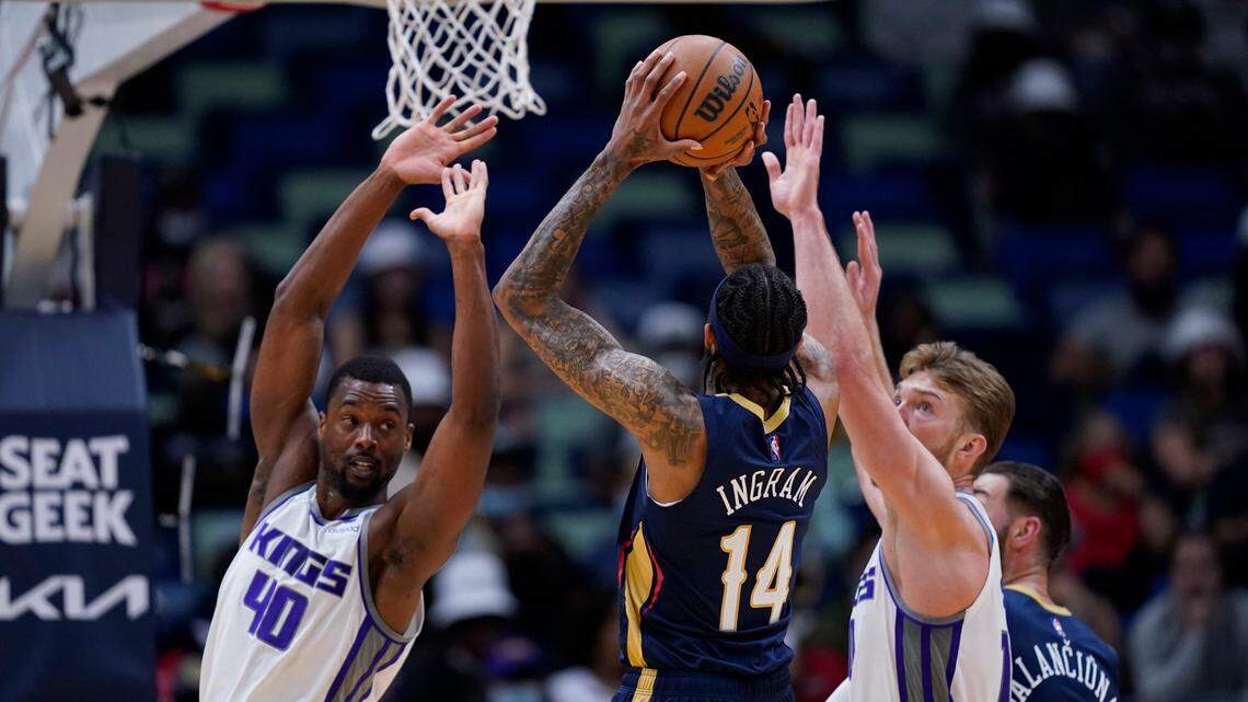 New Orleans Pelicans forward Brandon Ingram (14) shoots against Sacramento Kings forward Harrison Barnes (40) and forward Domantas Sabonis in the first half of an NBA basketball game in New Orleans, Wednesday, March 2, 2022. (AP Photo/Gerald Herbert)