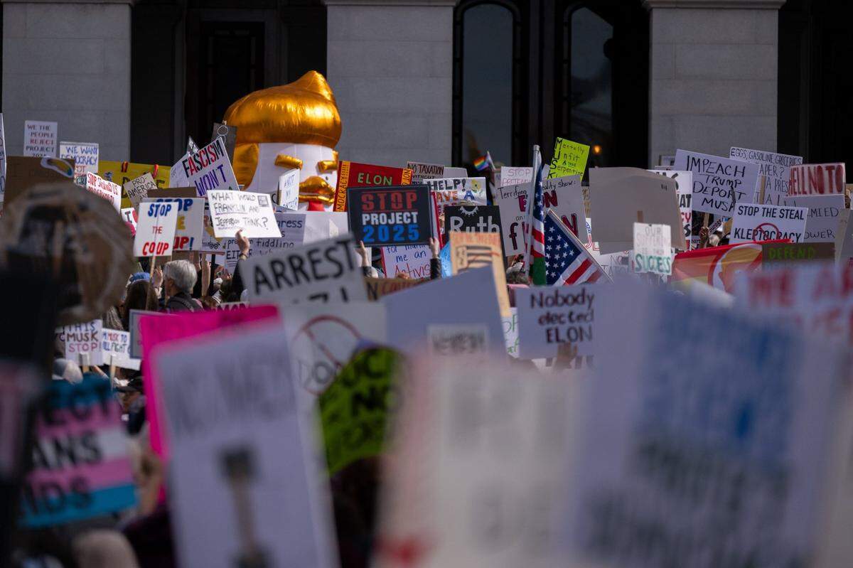 An infaltable caricature of President Donald Trump peeks above signs during a President’s Day protest on Monday at the state Capitol organized by the members of the grassroots 50501 Movement.