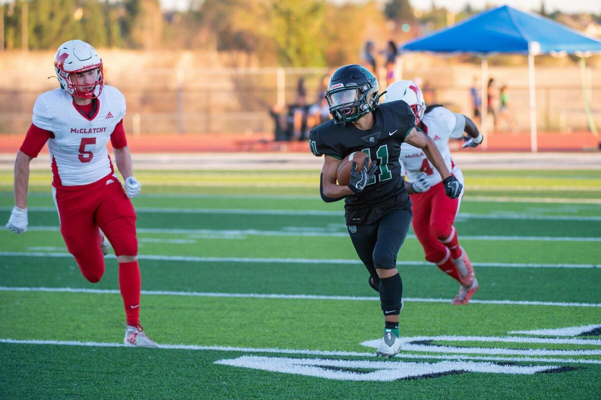 Twelve Bridges’ Anthony Gallagher (11) runs the ball past McClatchy’s Jonathan Godbout (5) during the first quarter in the game Friday, Aug. 19, 2022, at Twelve Bridges High School in Lincoln. Gallagher scored two touchdowns in the first half.