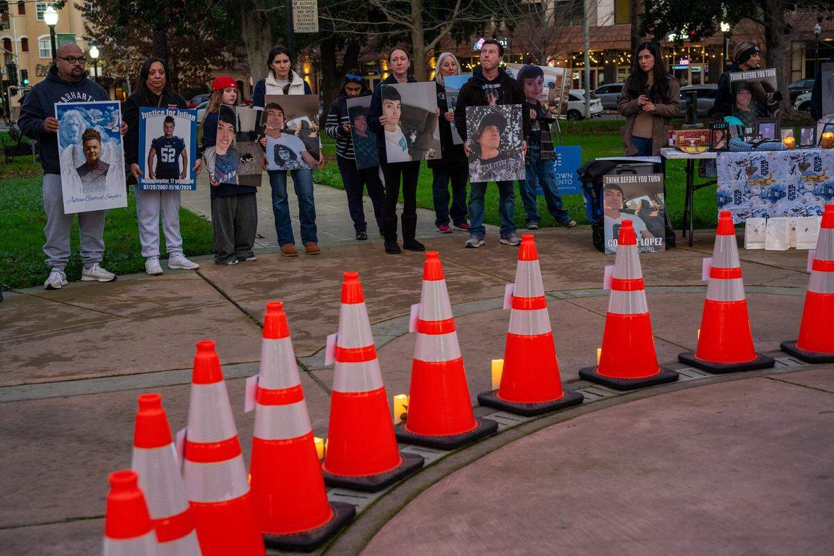 Family members of the victims of traffic deaths hold signs honoring their loved ones during the second annual vigil for lives lost to vehicular crashes within Sacramento city limits at Fremont Park in Sacramento on Wednesday, Jan. 7, 2026. Traffic cones bear the names of the 32 victims who died. Twelve were unhoused.