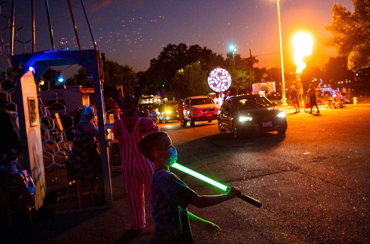 Ten-year-old Orion Woods, of Dixon, who has been to the Burning Man festival five times with his family, plays with a lightsaber while staying close to his mother, Sachi Woods, and the “Unicorner” camp’s display at the Summer Spark drive-thru festival on Friday, July 24, 2020, on Mine Shaft Lane in Rancho Cordova. “Since I haven’t left the house in months, this was an excuse to dress up,” said Sachi Woods. “So I can represent my camp and all my unicorn-y friends.” The two-night event concluded Saturday and featured a number of art elements from the 2019 Burning Man festival.