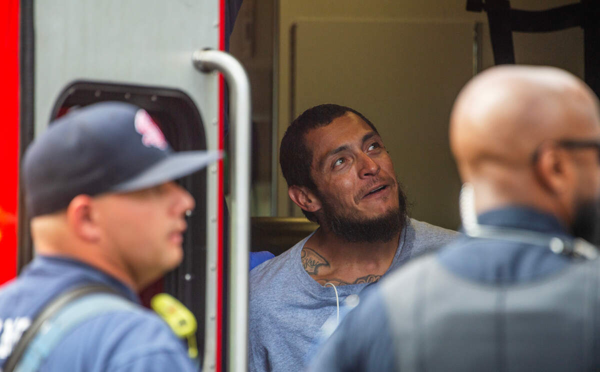 The carjacking suspect speaks to Sacramento Police officers from the back of an ambulance in the parking lot of the Del Taco on Alhambra Boulevard on Friday before he was transported to be medically examined.