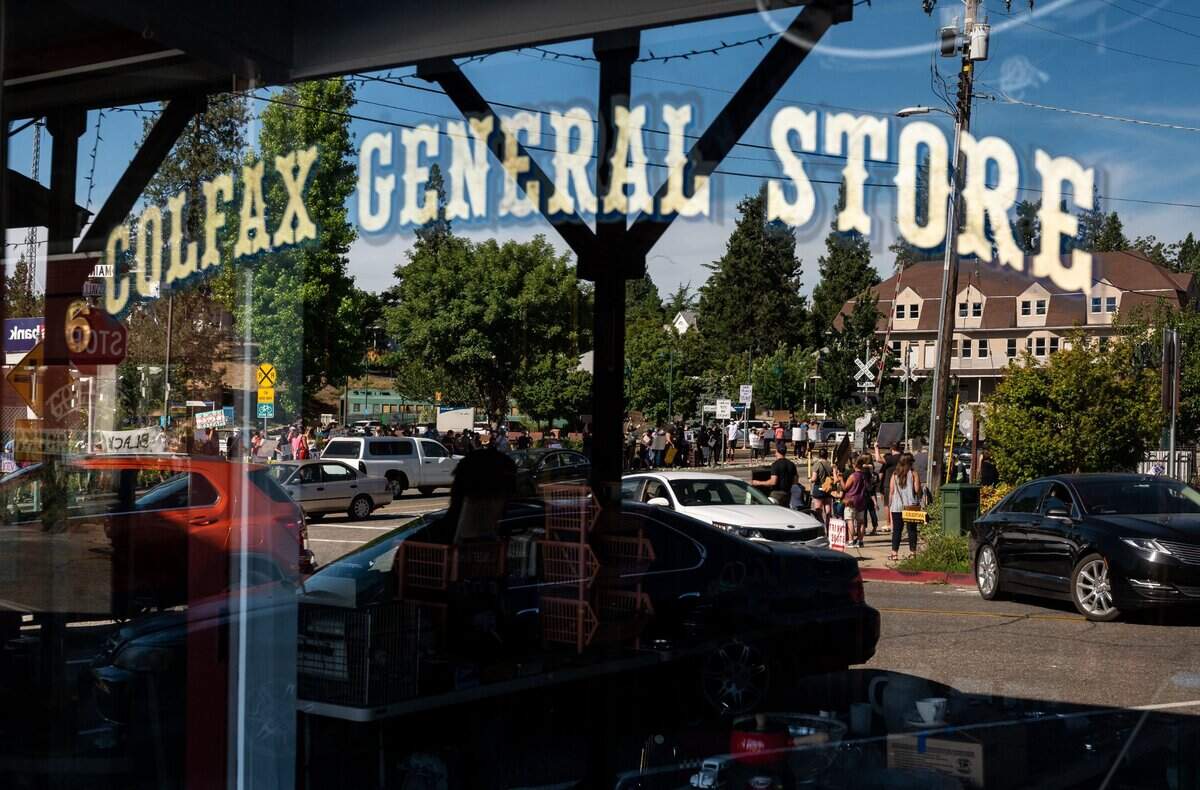 Protesters rallying against racial injustice in Colfax are seen in the window of the Colfax General Store on Wednesday.