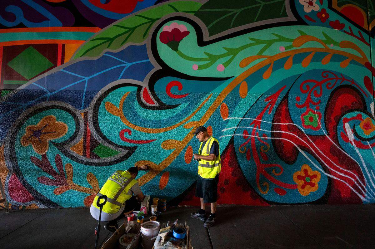 Artist Henry Fisk, aka “Fisko,” left, works in September with José Lott on a mural in the Second Avenue Highway 99 underpass.