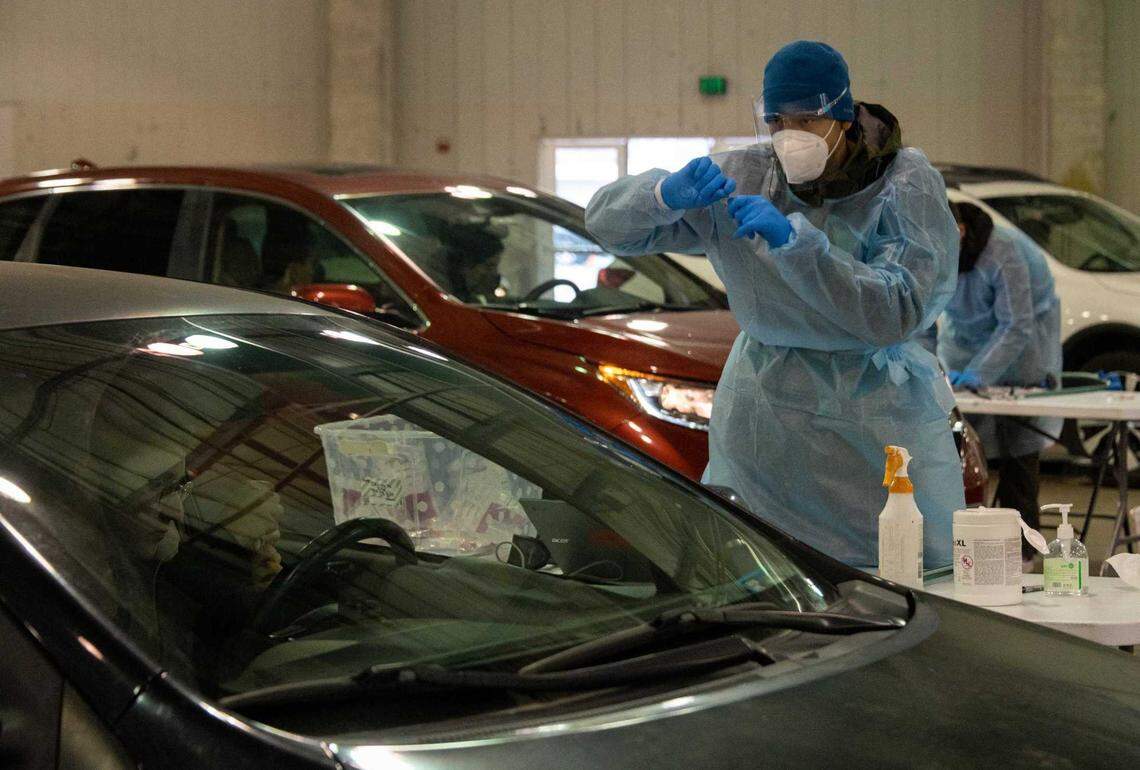 Testing site specialist Thomas Conley explains to a patient how to collect a sample at a Curative COVID-19 testing site Dec. 22, 2021, in Sacramento. Federal money to test uninsured people for free has run out. While some states are scrambling to fill the gap, California is meeting demand â for now.
