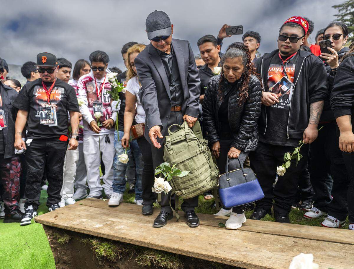 Jhony Ramos Sr. drops a flower into the grave of his sons Jesus and Jhony Ramos at Greenlawn Memorial Park in Colma on Monday, July 28, 2025. The brothers were killed at a fireworks facility explosion in Esparto.