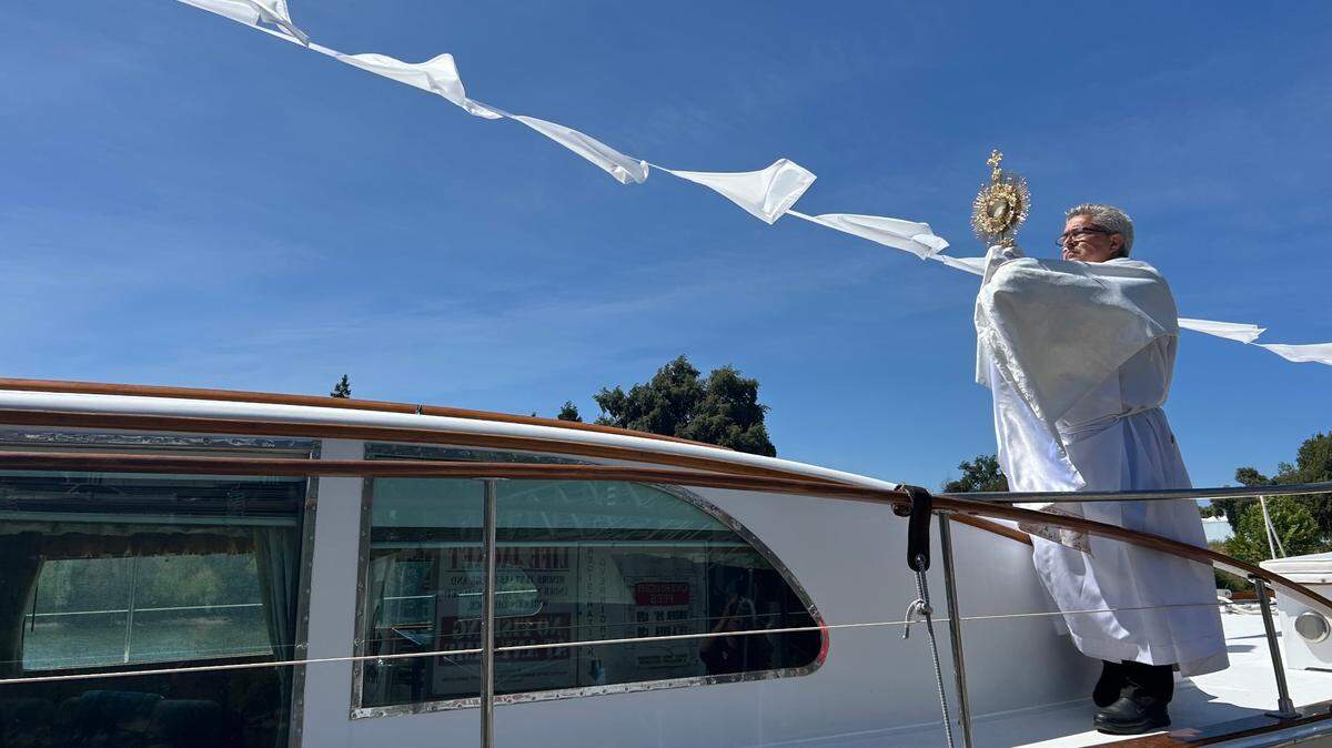 Deacon Kevin Staszkow holds the Eucharist aboard the Aurora V on Friday. Moments later, the boat departed from Walnut Grove for its next stop in Clarksburg.