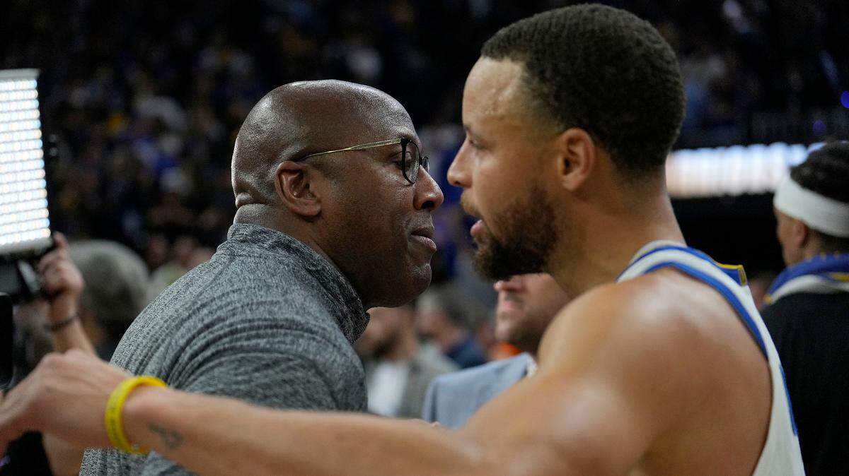 Golden State Warriors assistant coach Mike Brown, left, hugs Stephen Curry after a 101-98 victory against the Memphis Grizzlies during the second half of Game 4 of an NBA basketball Western Conference playoff semifinal in San Francisco, Monday, May 9, 2022. (AP Photo/Tony Avelar)