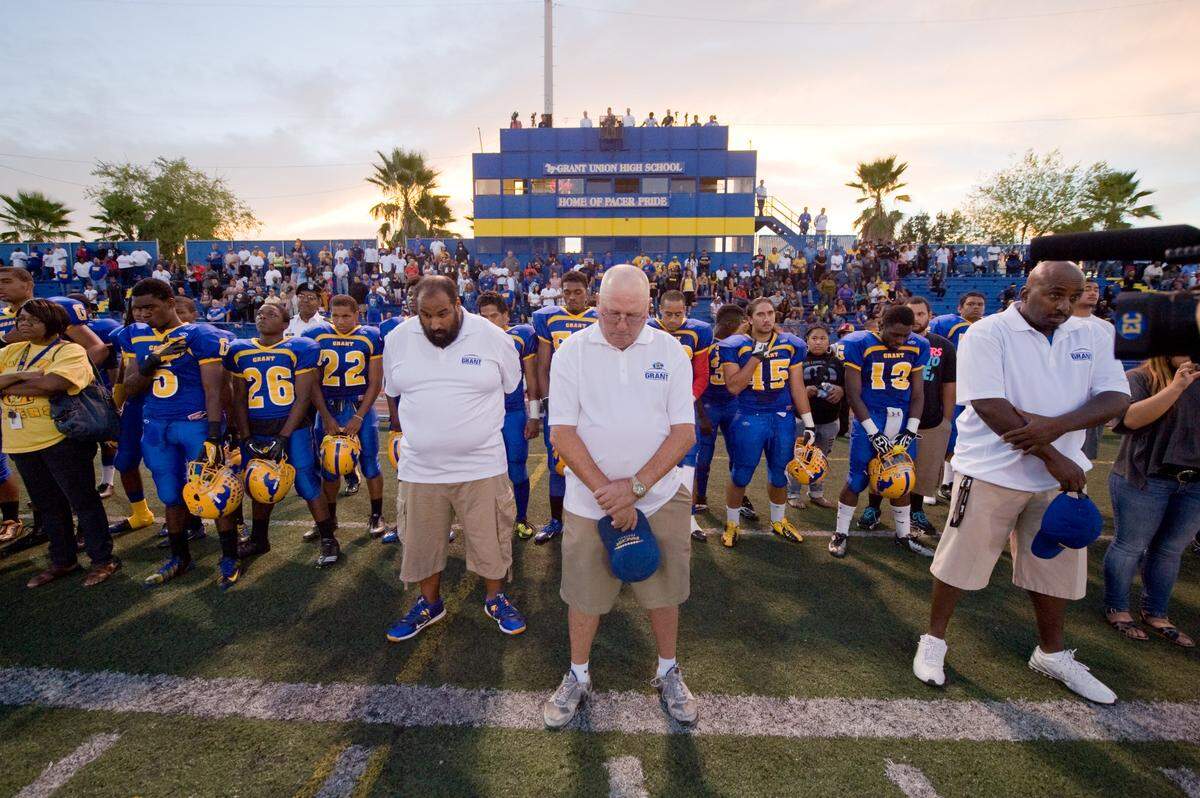 Grant High School’s head coach Mike Alberghini, center, coaches and players observe a moment of silence for former Grant High School assistant coach Edward Coleman before the game at Grant against Del Oro High School, Friday, Sept. 21, 2012.