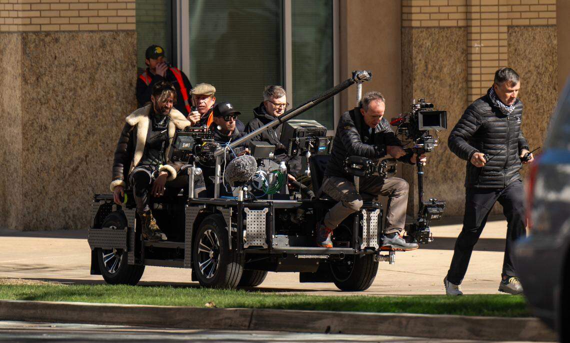 Director Paul Thomas Anderson, center, watches a screen on a film vehicle as his cinematography crew runs through a chase shoot for his Warner Bros. movie in front of Sacramento’s City Hall on Saturday, Feb. 10, 2024.