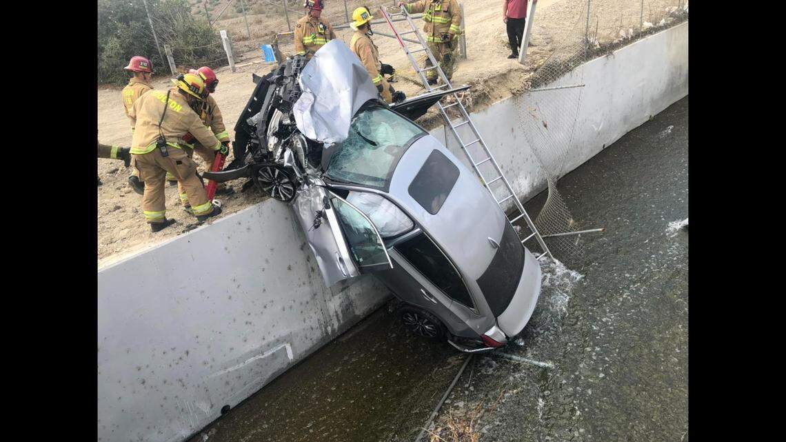 A head-on collision left two people trapped inside a car dangling over a rushing canal near Colton, California firefighters say.
