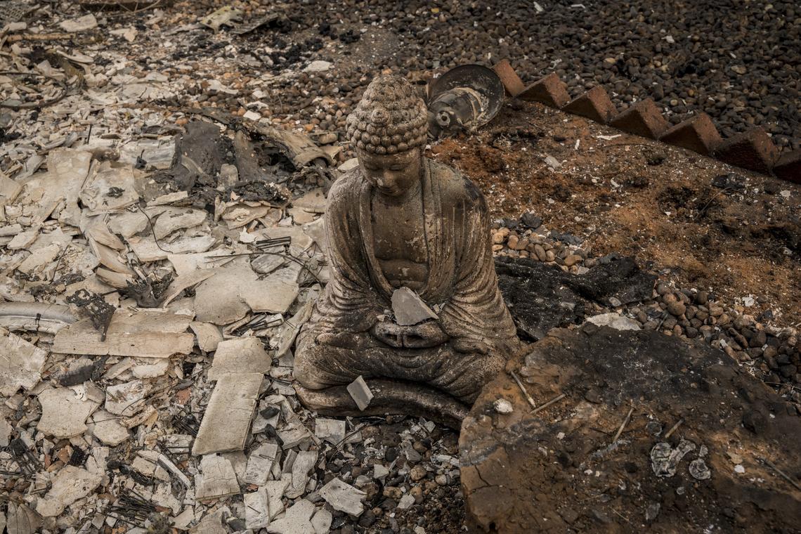 A shard of ceramic sits in the hands of a Buddha statue at the Pine Springs Mobile Home Park after the deadly Camp Fire swept through, destroying most of the homes in the park.