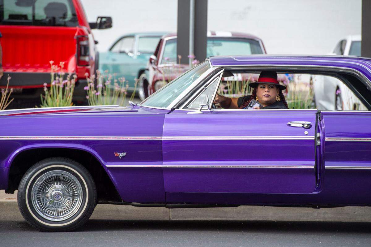 Tessa Cordell of Lincoln gets out of her purple 1964 Impala during a lowrider event on Broadway on Saturday.